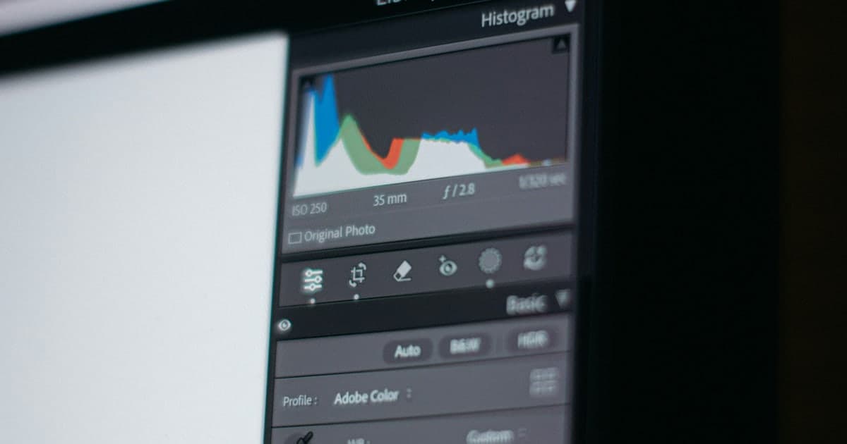 A photo editing panel on a monitor showing a histogram with ISO, focal length and aperture values